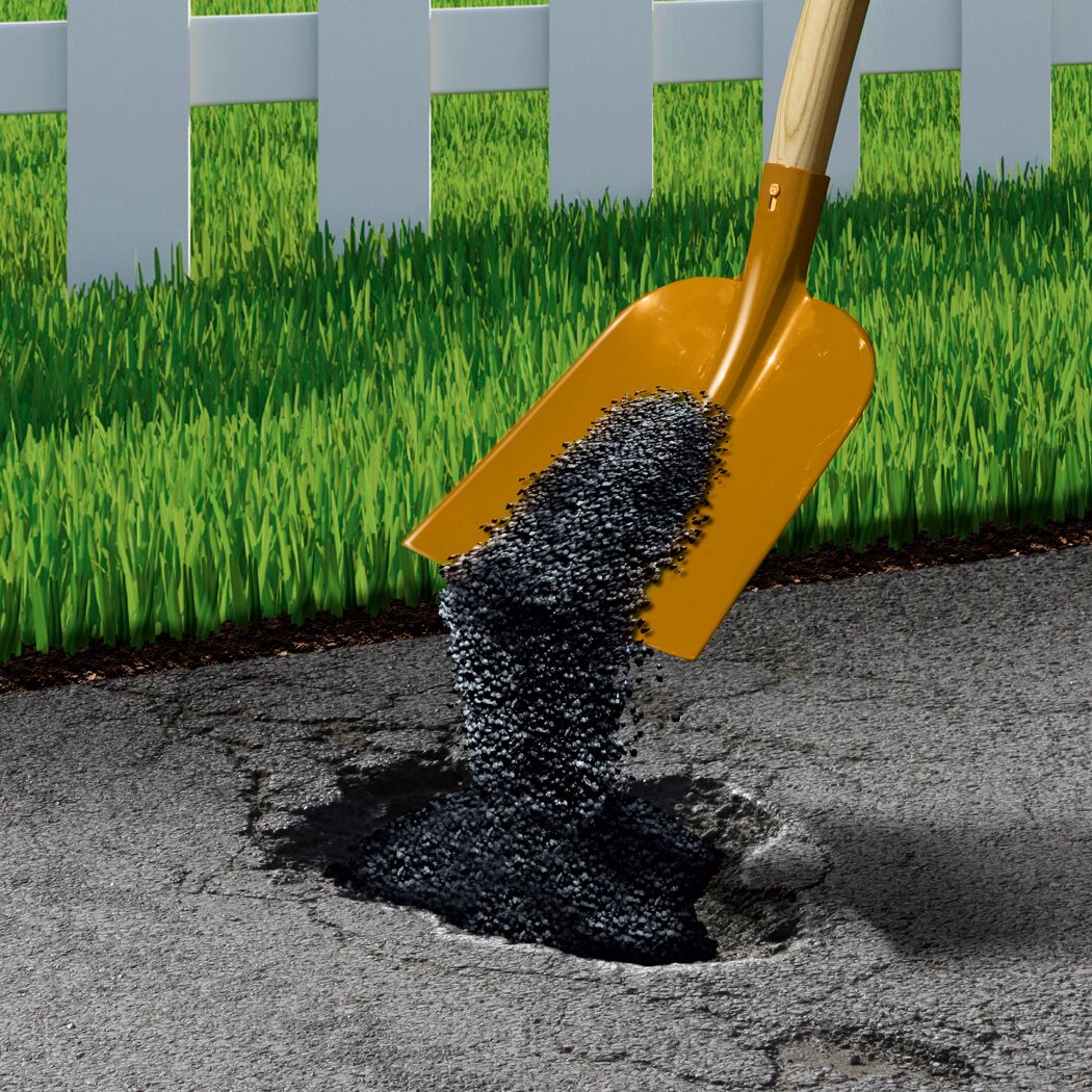Asphalt wird mit einer Schaufel in ein Loch gefüllt.