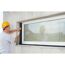 Person bringt Fensterband an Fenster an.