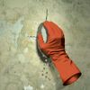 Eine Person trägt einen orangefarbenen Handschuh und reibt mit einem Schwamm über eine Wand.