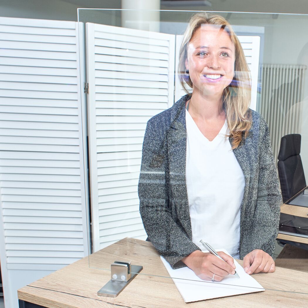Person schreibt hinter Plexiglas-Thekenaufsatz
