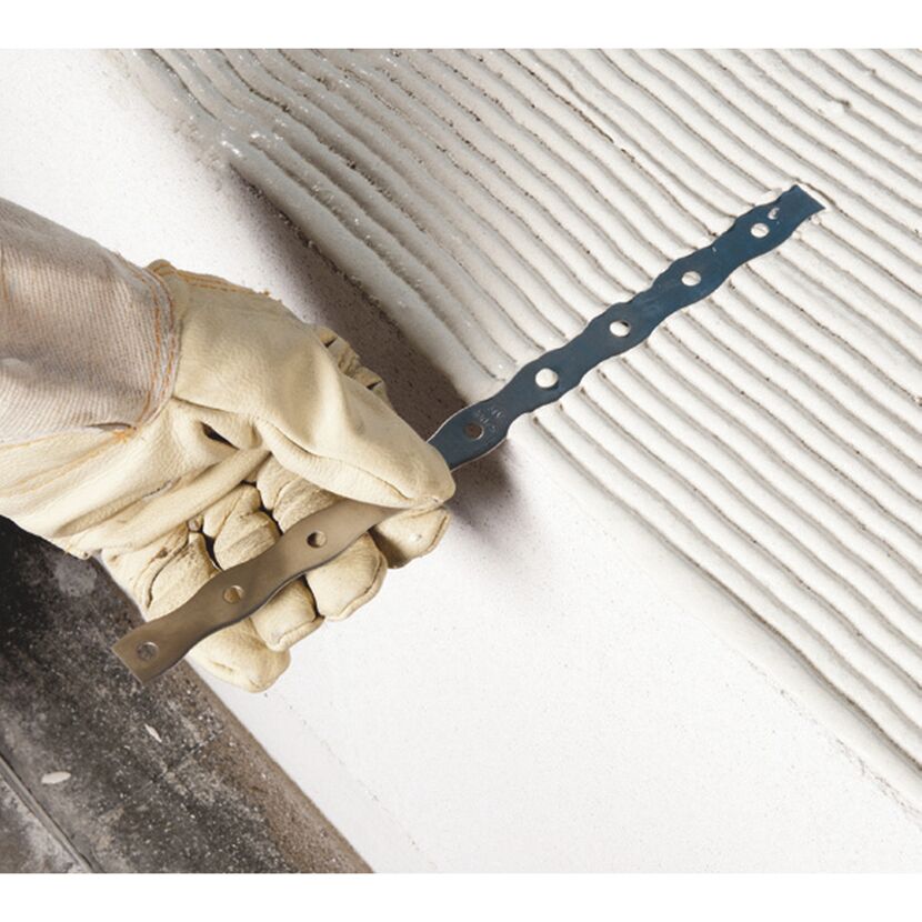 Person trägt Handschuh und hält Mauerverbinder