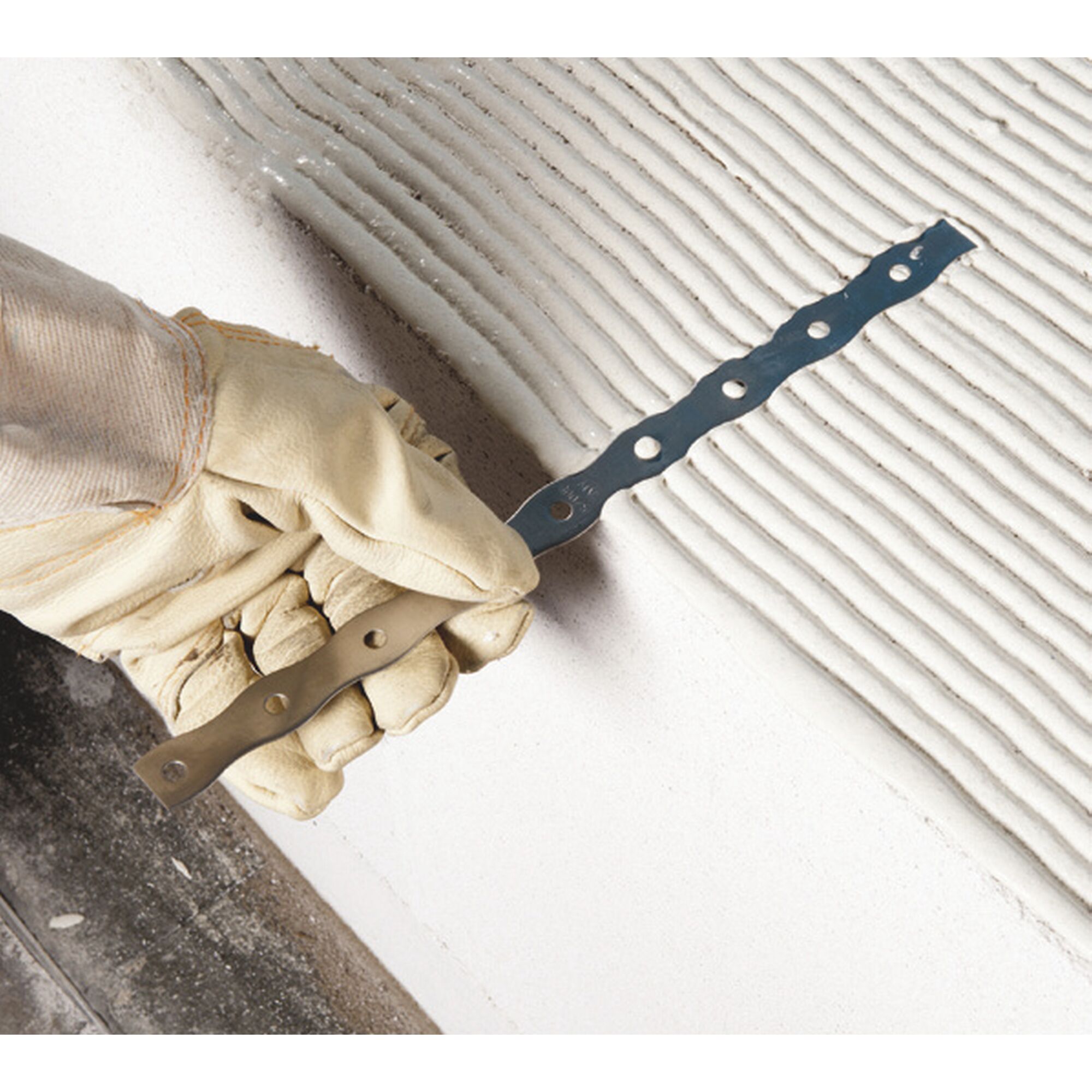 Person trägt Handschuh und hält Mauerverbinder