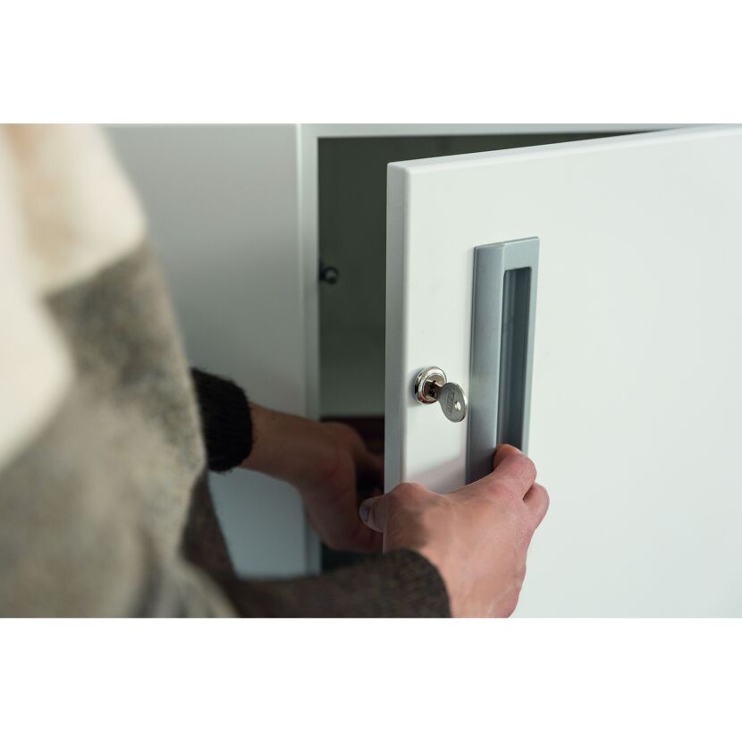 Person schließt einen Schrank mit einem Schlüssel auf.