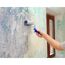 Person streicht eine Wand mit einer Farbrolle.