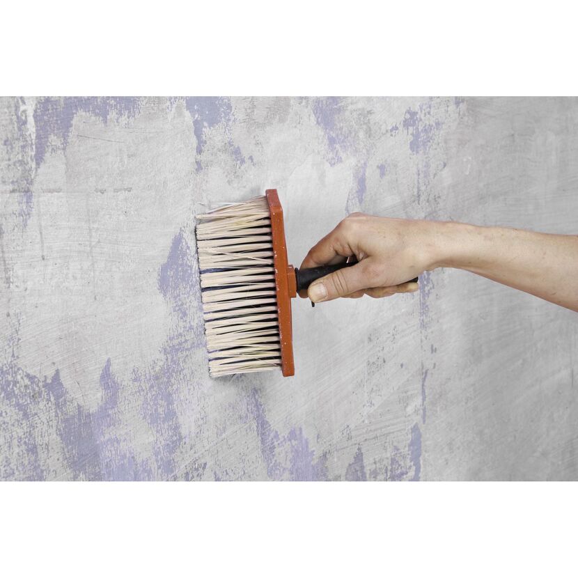Person grundiert eine Wand mit einem Pinsel.