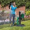 Person bewässert Garten mit Gartenschlauch und Gießkanne.