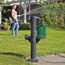 Person gießt mit Gartenschlauch eine Gießkanne.