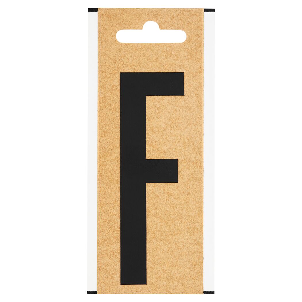 Schwarzer Folienbuchstabe F auf braunem Karton