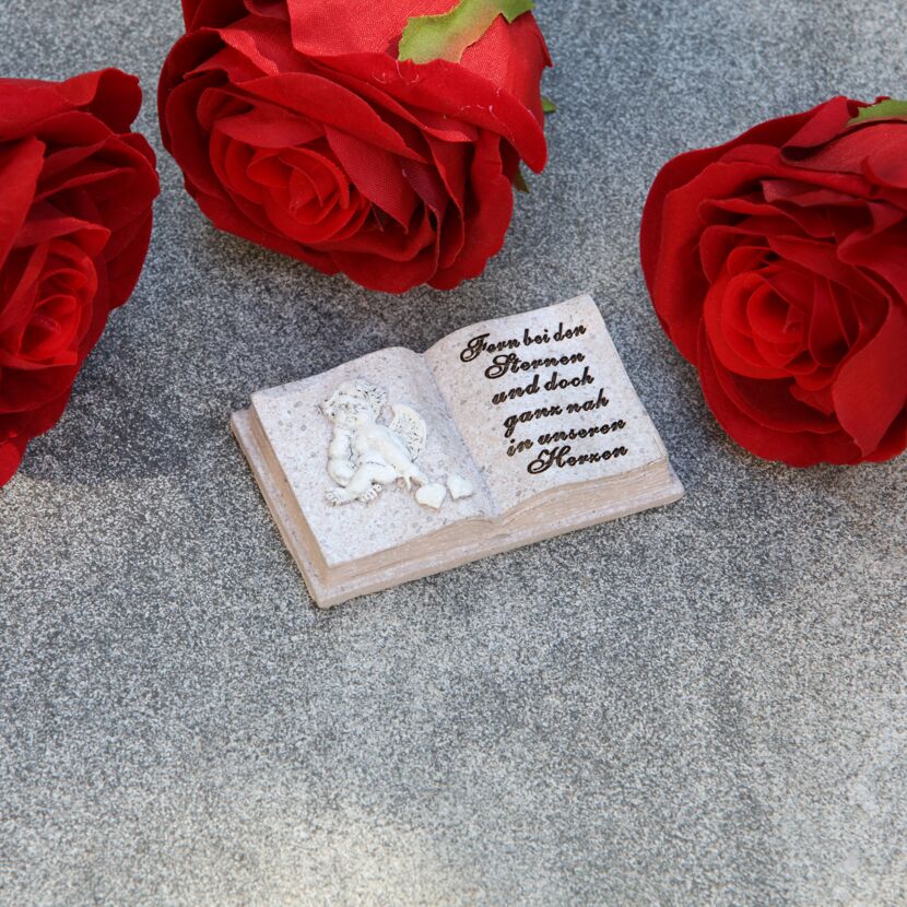 Drei rote Rosen und ein Grabdekobuch mit Engel