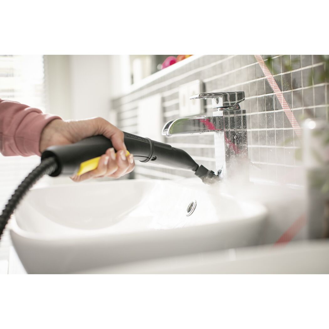 Person reinigt Waschbecken mit Dampfreiniger.
