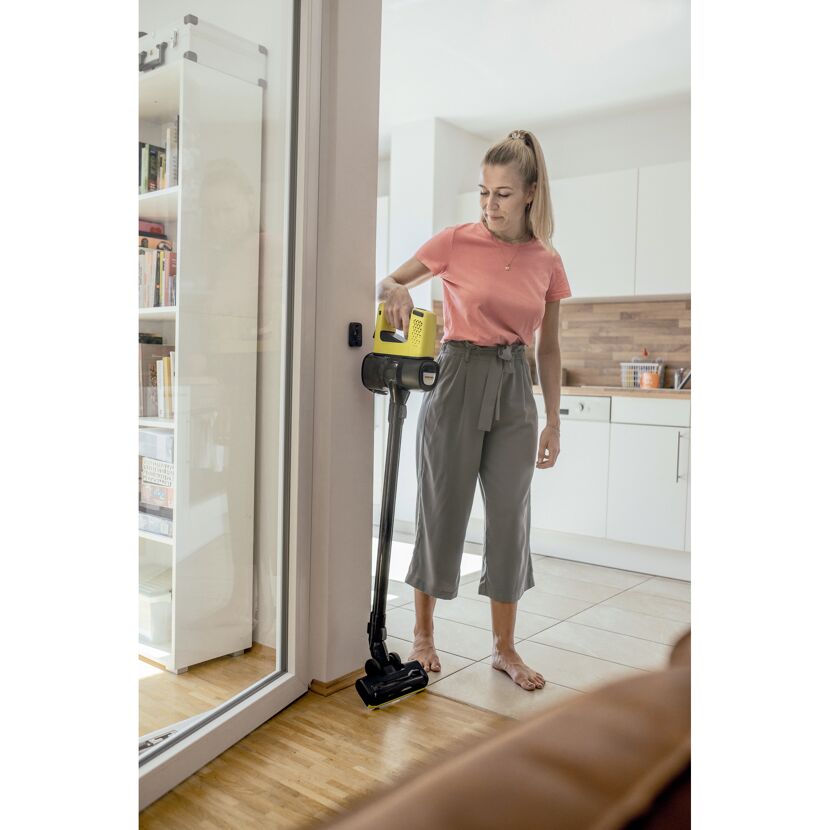 Person saugt mit einem Stielstaubsauger