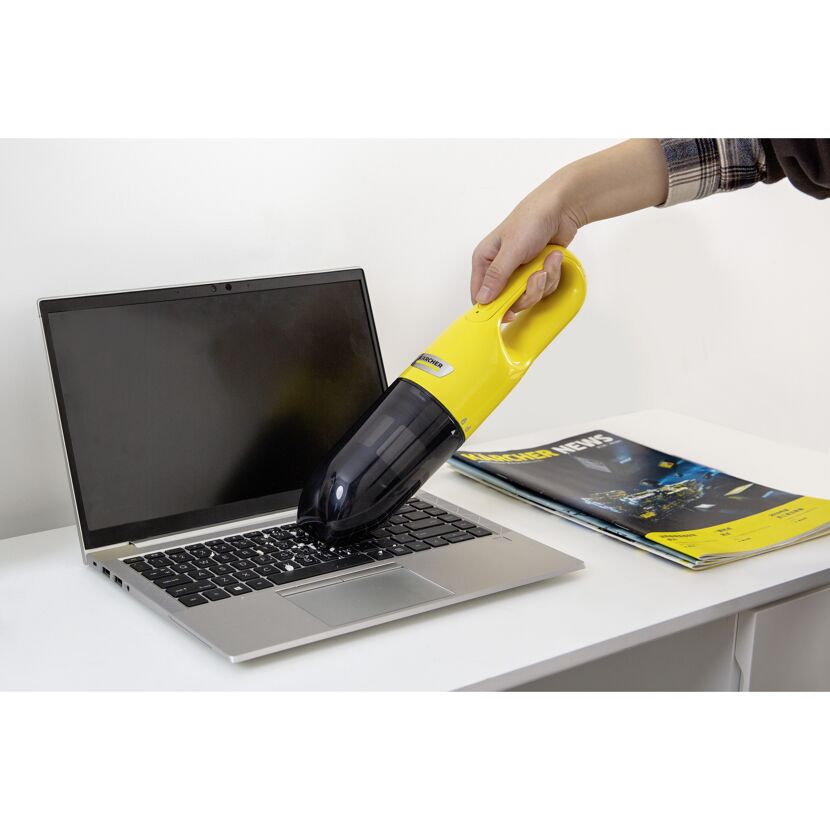 Person reinigt Laptoptastatur mit Handstaubsauger
