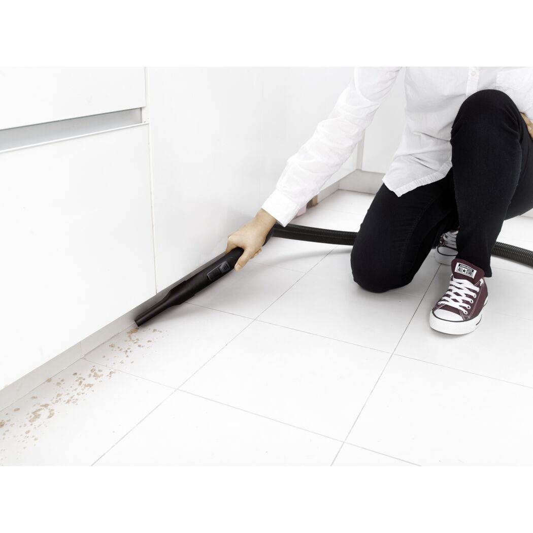 Person saugt Krümel mit Staubsauger auf