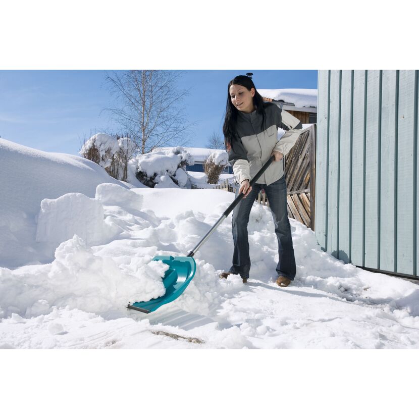 Person räumt Schnee mit Schneeschieber