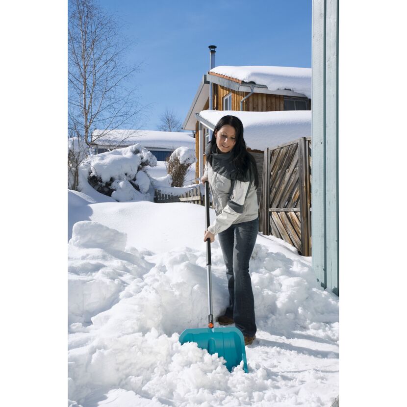 Person räumt Schnee mit Schneeschieber