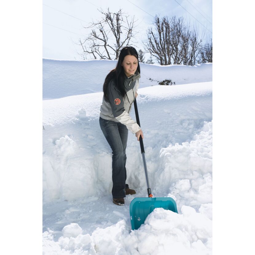 Person räumt Schnee mit Schneeschieber