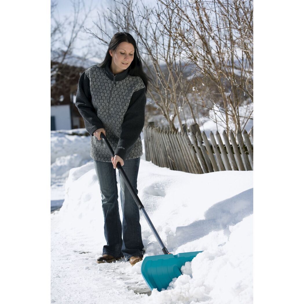 Person räumt Schnee mit Schneeschieber