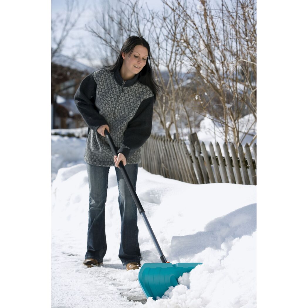 Person räumt Schnee mit Schneeschieber