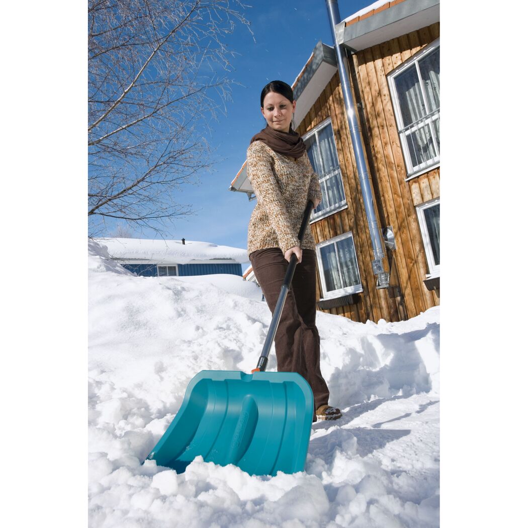 Person räumt Schnee mit Schneeschieber