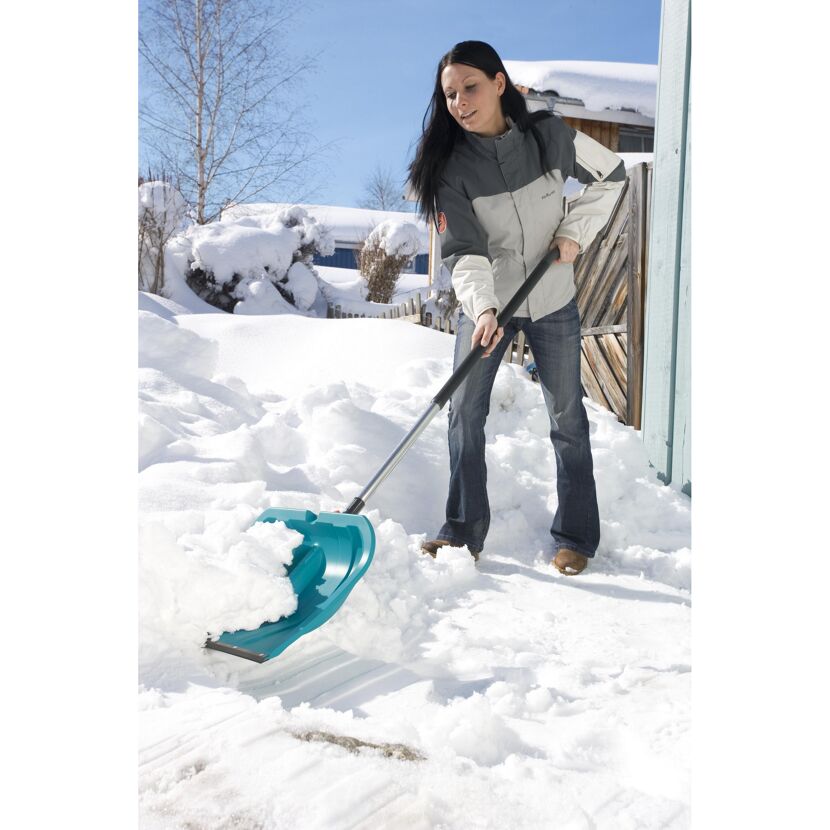 Person räumt Schnee mit Schneeschieber