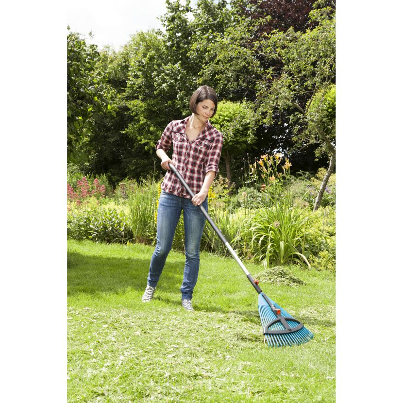 Person rechen mit Laubbesen im Garten