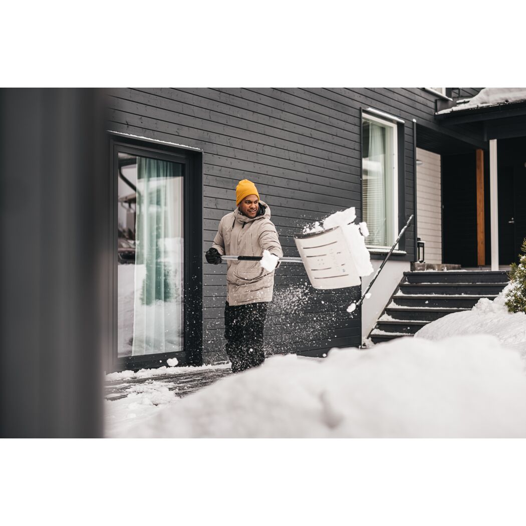 Person räumt Schnee mit Schneeschieber