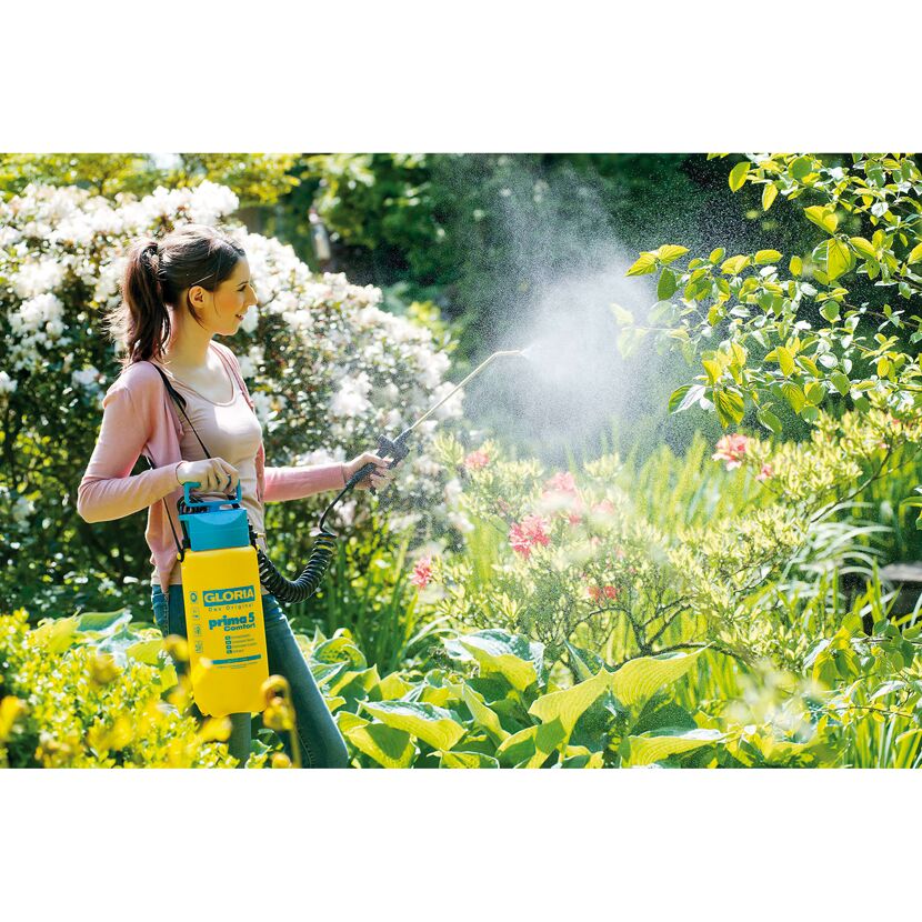 Person benutzt Drucksprühgerät im Garten