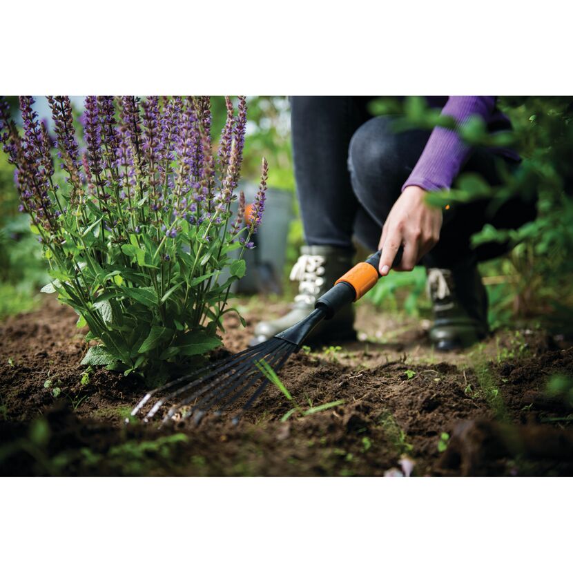 Person harkt Erde mit Fiskars QuikFit Kleinfächerbesen