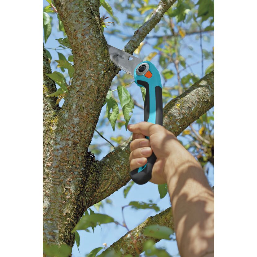 Person sägt mit Gartenklappsäge einen Ast ab.