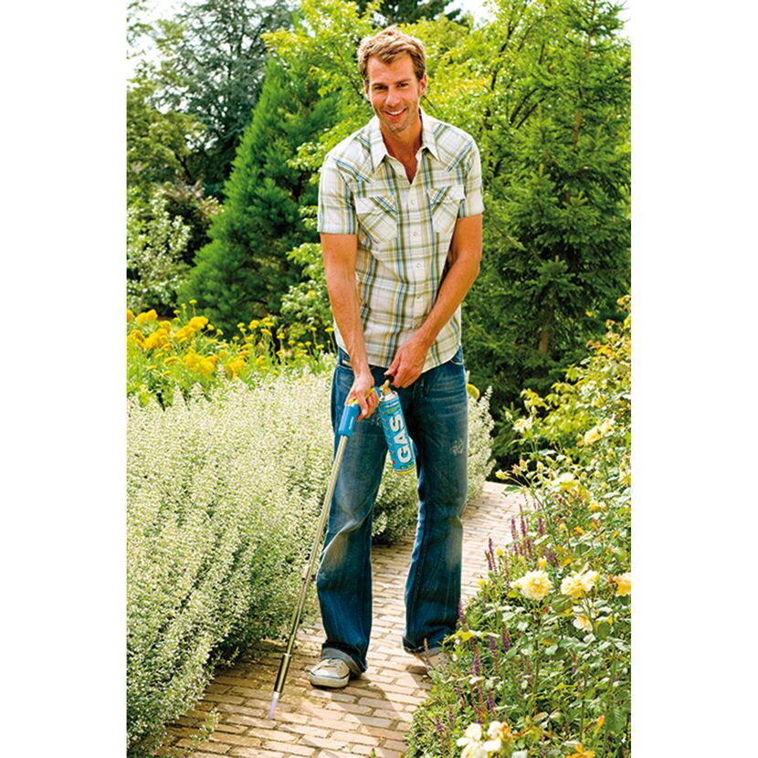Person verwendet einen Thermoflamm Comfort Abflammgerät im Garten.
