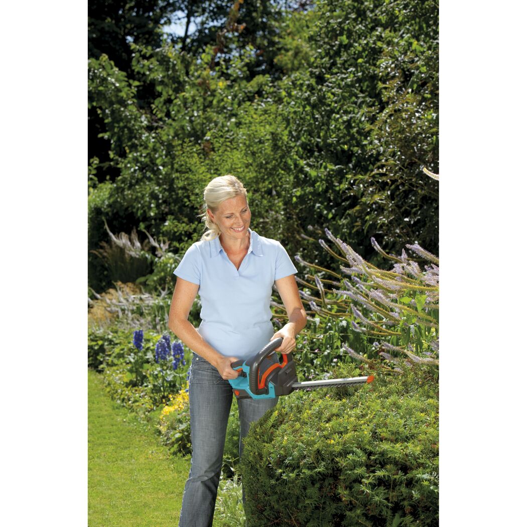 Person schneidet Hecke mit Akku-Heckenschere.