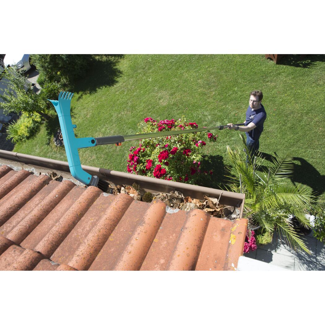 Person reinigt Dachrinne mit Teleskopstiel