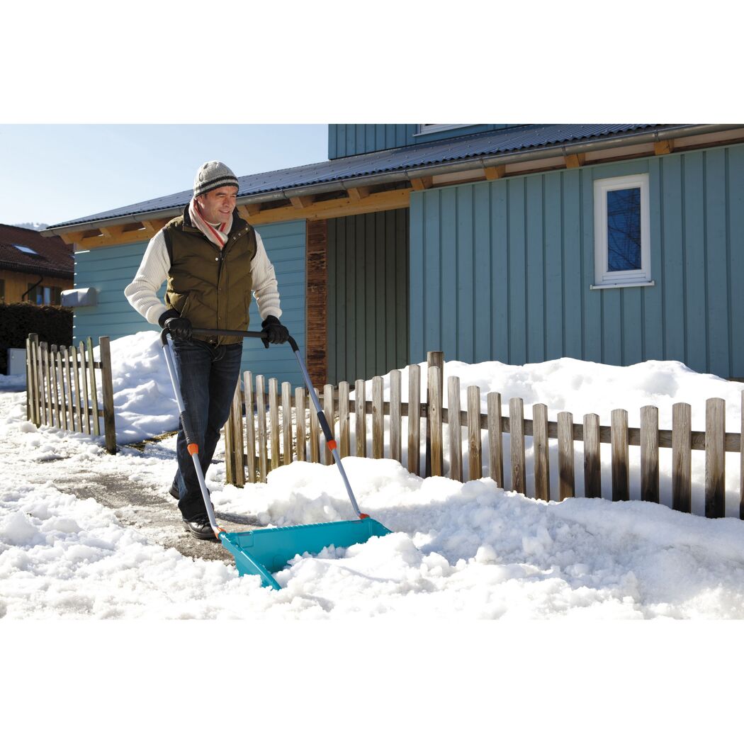 Person räumt Schnee mit Schneeschieber