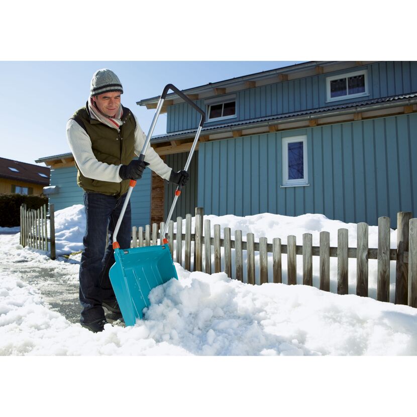 Person räumt Schnee mit Schneeschieber