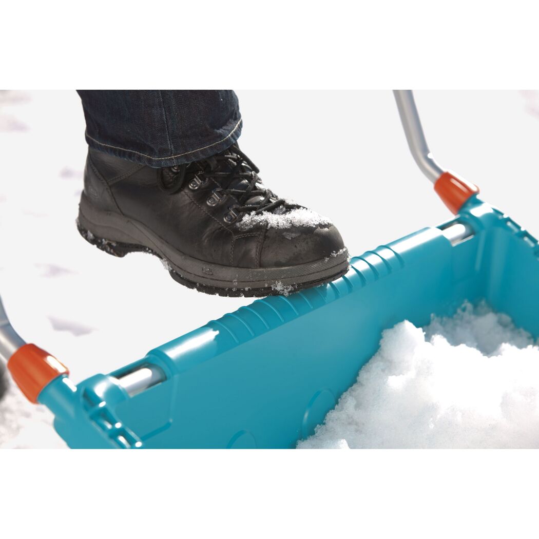 Person schiebt Schnee mit Schneeschieber