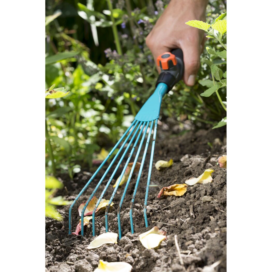 Person verwendet einen Handfeger im Garten.
