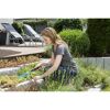 Person jätet mit Handrechen Unkraut im Garten.