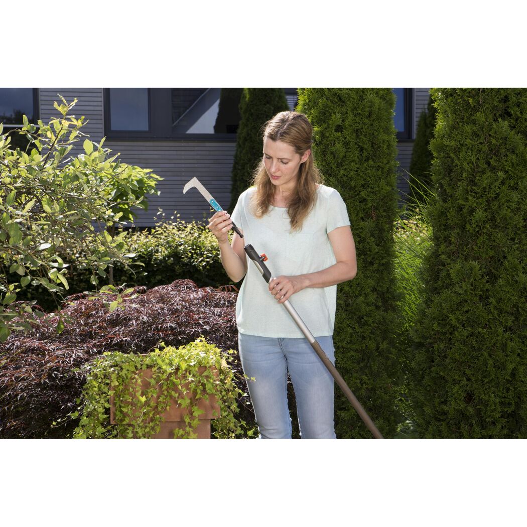 Person verwendet Fugenkratzer im Garten.