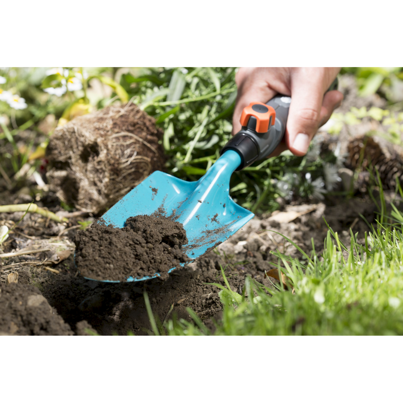 Person gräbt mit Blumenkelle Erde um