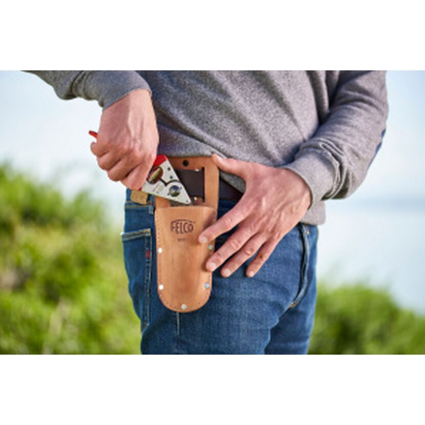 Person steckt eine Felco-Schere in eine Ledertasche.