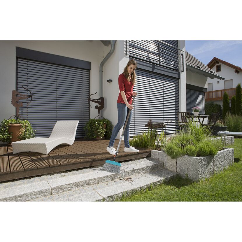 Person fegt Terrasse mit Besen