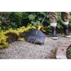 Person harkt Kiesweg mit Laubbesen