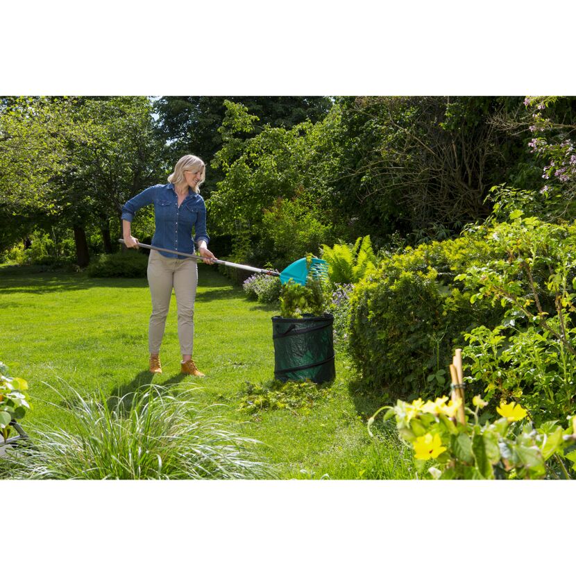 Person verwendet Schaufelrechen im Garten.