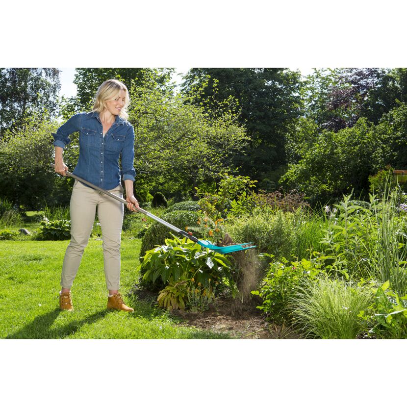 Person jätet mit dem Combisystem-Schaufelrechen Unkraut im Garten