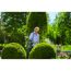 Person sprüht mit Drucksprüher Pflanzen im Garten.