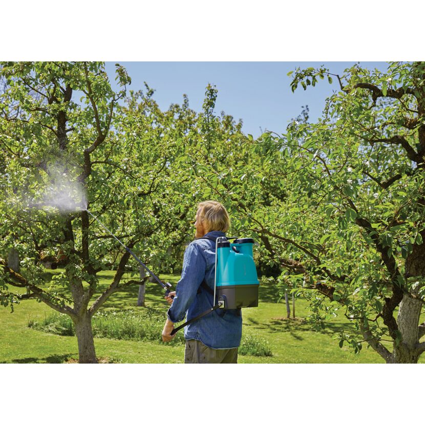 Person benutzt Rückenspritzgerät im Garten.