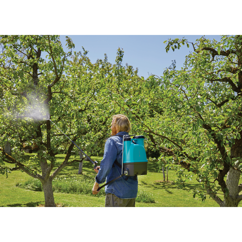 Person benutzt Rückenspritzgerät im Garten.