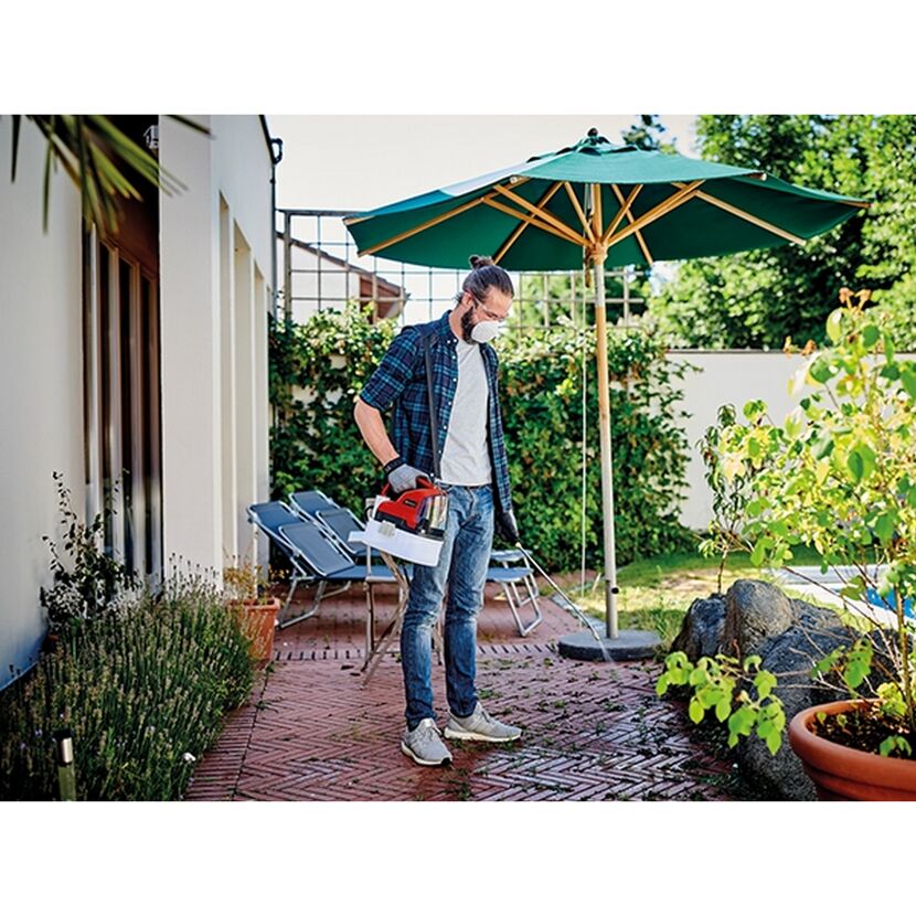 Person benutzt Akku-Drucksprüher im Garten.
