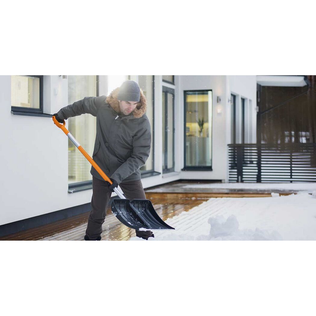 Person räumt Schnee mit Schneeschieber