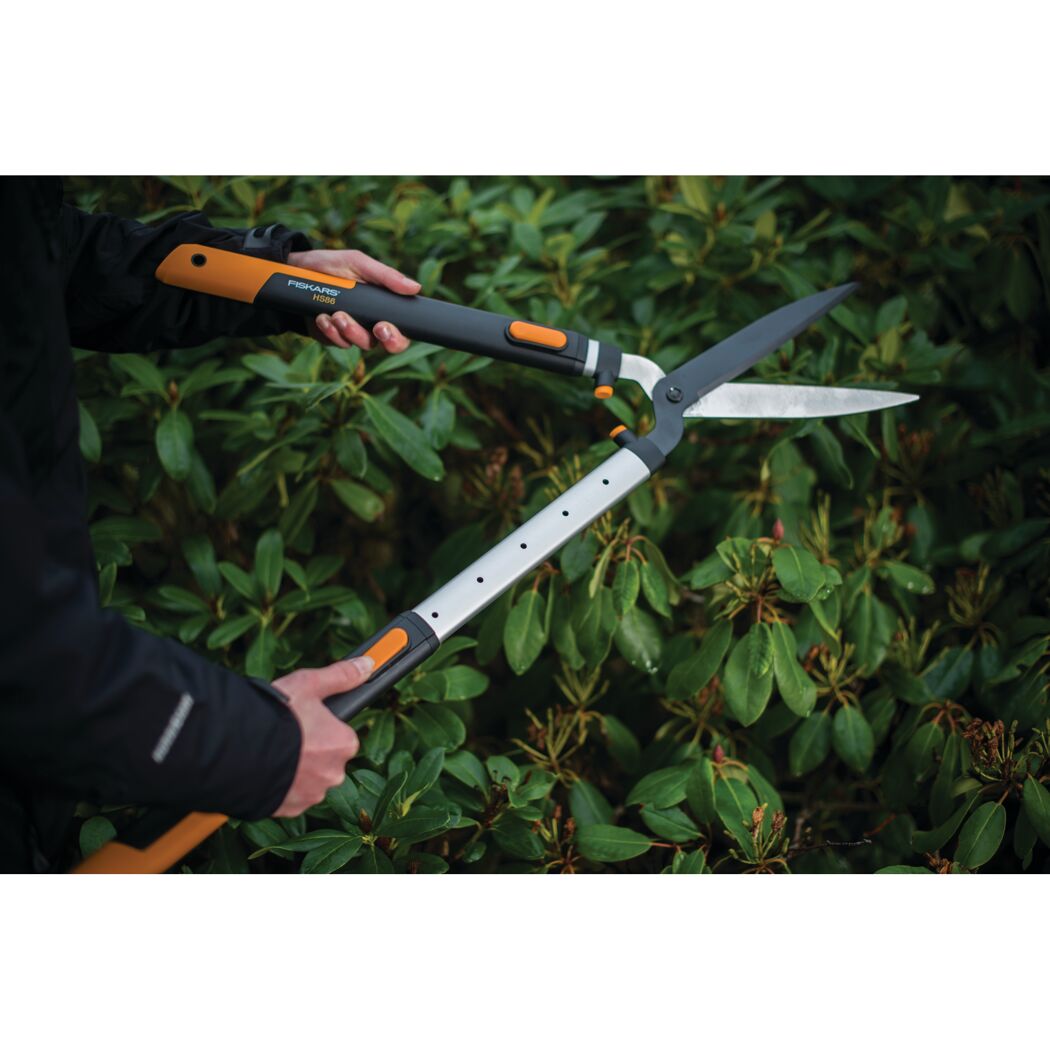 Person verwendet eine Fiskars Teleskopheckenschere SmartFit.